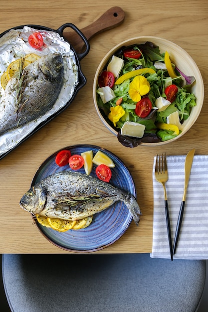 Cozinha mediterrânea na mesadorada do forno com salada e queijo travessa de queijo com nozes e salada nutrição adequada na mesa legumes com peixe assadopeixe prontodorado grill