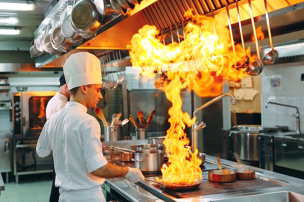 Cozinha moderna. Os cozinheiros preparam refeições no fogão, na cozinha do restaurante ou do hotel.