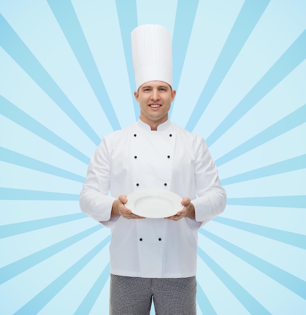 cozinha, profissão, propaganda e conceito de pessoas - cozinheiro chef masculino feliz mostrando algo no prato vazio sobre fundo de raios de explosão azul