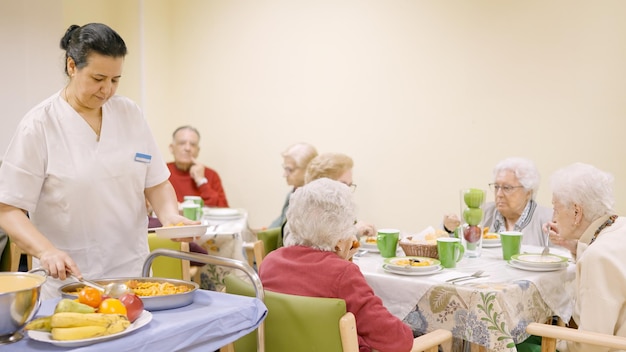 Foto cozinha servindo comida a idosos em um geriátrico