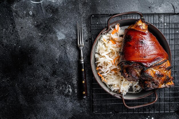 Cozinha tradicional alemã Junta de porco assada Schweinshaxe com chucrute Fundo preto Vista de cima Espaço para cópia