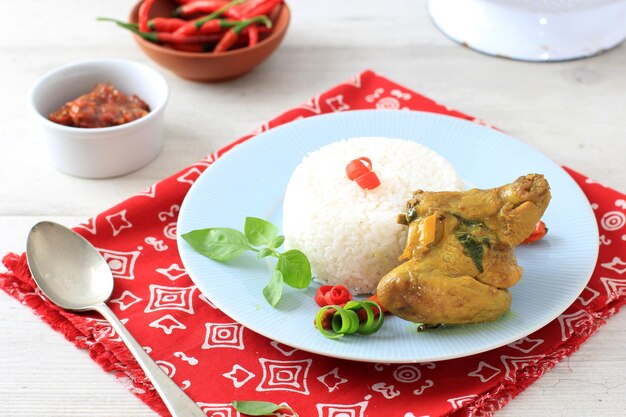 Cozinha tradicional indonésia: ayam woku, ou frango com especiarias a cúrcuma com manjericão doce asiático, um prato de frango manadonês servido com arroz