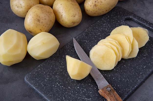 Cozinhando. Cortar batatas frescas em fatias em uma tábua