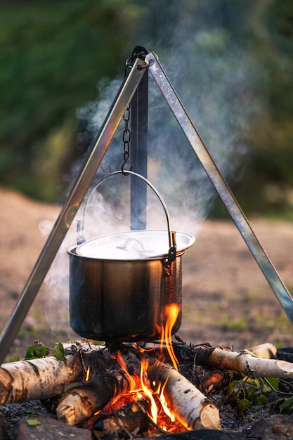 Cozinhando em uma fogueira em um caldeirão em uma caminhada