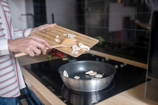 Cozinhando. foto aproximada de uma mulher colocando vegetais em uma frigideira