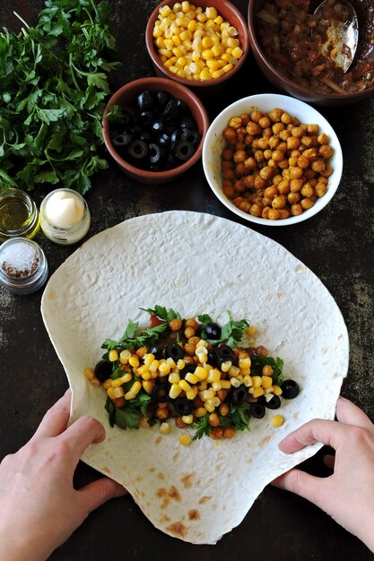 Cozinhando shawarma vegano. As mãos em luvas culinárias impõem um recheio no pão pita para fazer shawarma. Cozinha do Oriente Médio.