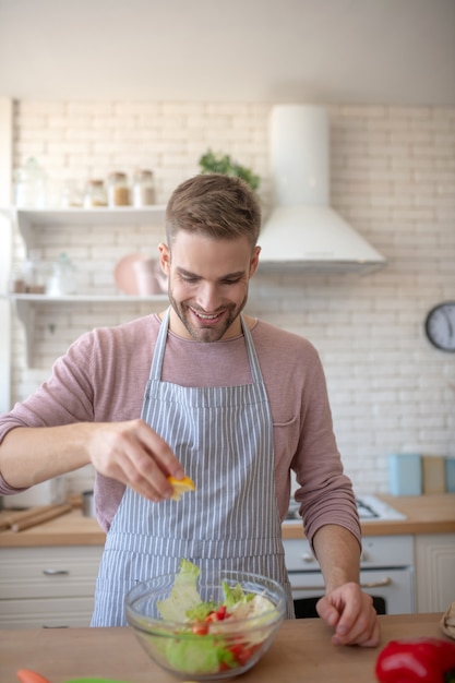 Cozinhando. Um homem servindo uma salada fresca com suco de limão