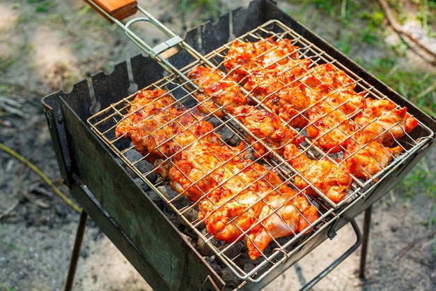 Cozinhar asas e pernas de frango na grelha Carne assada na grelha em close-up