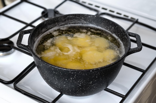 Foto cozinhar batatas em uma panela com água fervente em um fogão a gás