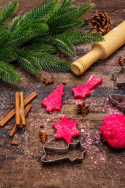 Cozinhar biscoitos de gengibre vermelho. doces tradicionais de natal. árvore do abeto, especiarias, cortadores de biscoito, massa crua, rolo, tábuas de madeira