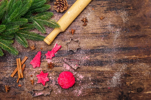 Cozinhar biscoitos de gengibre vermelho. Doces tradicionais de Natal. Fundo culinário festivo. Árvore do abeto, especiarias, cortadores de biscoito, massa crua, rolo, tábuas de madeira