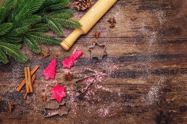 Cozinhar biscoitos de gengibre vermelho. Doces tradicionais de Natal. Fundo culinário festivo. Árvore do abeto, especiarias, cortadores de biscoito, massa crua, rolo, tábuas de madeira