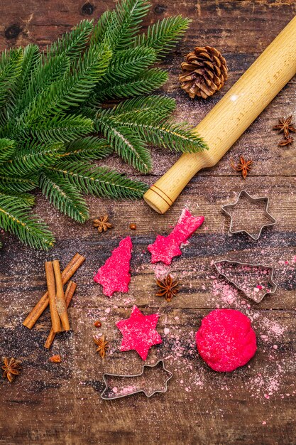 Cozinhar biscoitos de gengibre vermelho. Doces tradicionais de Natal. Árvore do abeto, especiarias, cortadores de biscoito, massa crua, rolo, tábuas de madeira