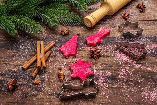 Cozinhar biscoitos de gengibre vermelho. Doces tradicionais de Natal. Árvore do abeto, especiarias, cortadores de biscoito, massa crua, rolo, tábuas de madeira