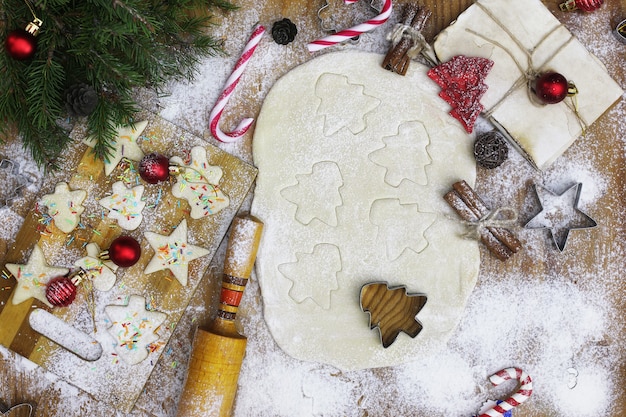 Cozinhar biscoitos de manteiga de diferentes formatos em uma mesa de madeira com acessórios de Natal