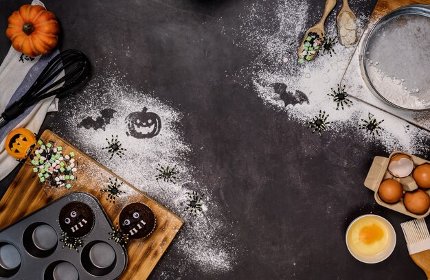 Foto cozinhar bolo de halloween festivo em casa. assar ingredientes caseiros com farinha em fundo escuro, com espaço de cópia para o texto.