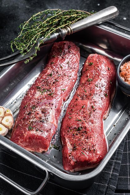 Cozinhar carne de filé de cordeiro com ervas e azeite de oliva marinado carne de carneiro na bandeja da cozinha Fundo preto Vista superior