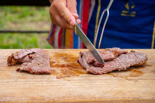 Foto cozinhar cortando carne grelhada na grelha