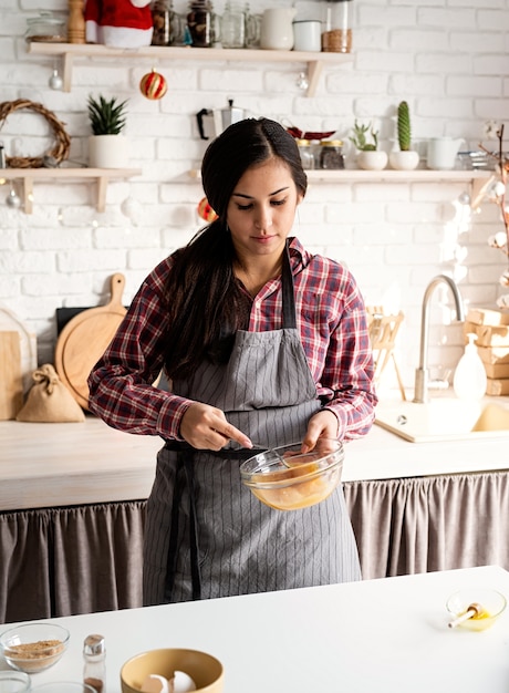 Cozinhar e assar Jovem mulher latina batendo ovos para cozinhar na cozinha