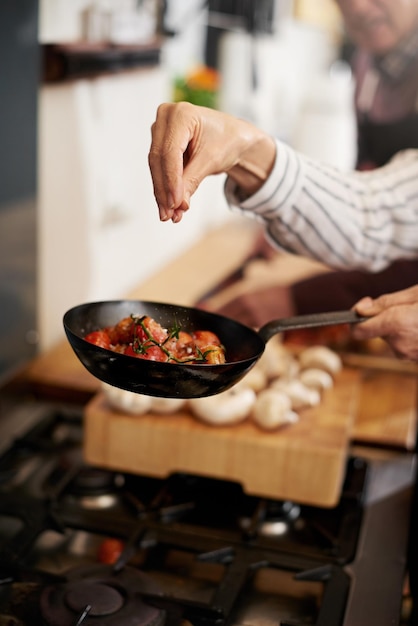 Foto cozinhar e temperar à mão com um chef na cozinha para preparação de refeições em uma casa para jantar dieta saudável e nutrição com comida em uma panela para fome de bem-estar ou satisfação em uma casa