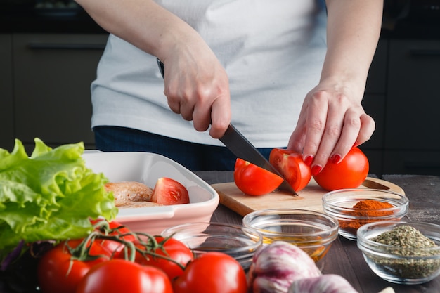 Cozinhar frango. feminino mão cortada com uma faca