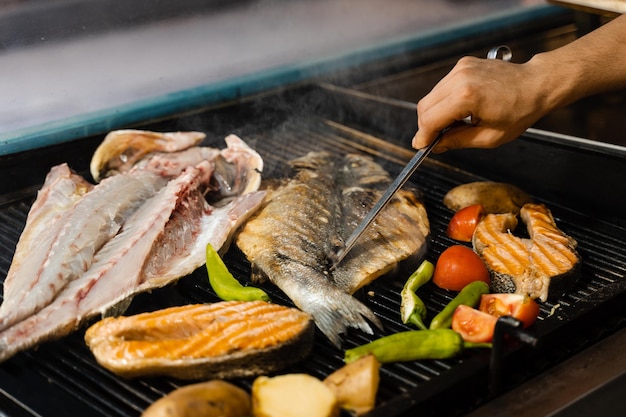 Cozinhar frutos do mar com uma mistura de salmão, robalo e vegetais. Grelhar o peixe com batata chili e tomate.