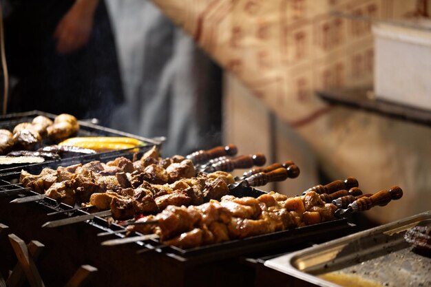 Cozinhar kebabs de carne em espigas em uma rua da cidade Comida de rua em feiras