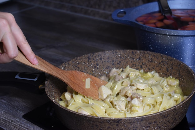 Cozinhar macarrão no fogão na cozinha em casa. chef mulher preparando o almoço