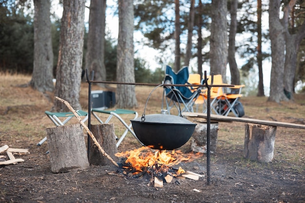 Cozinhar no caldeirão em fogo aberto na natureza Bowler na fogueira na floresta Panela de ferro fundido na fogueira no fundo do rio Copiar espaço