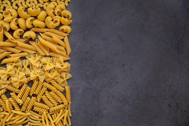 Cozinhar o conceito de comida Diferentes tipos de massa em uma superfície escura Vista de cima