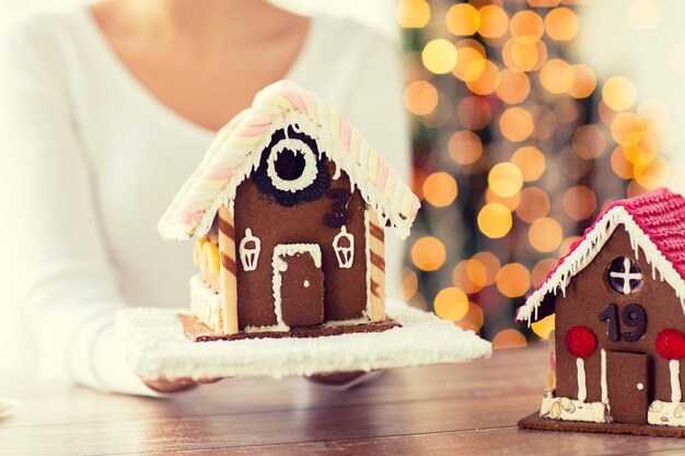 cozinhar, pessoas, natal e conceito de cozimento - close-up de mulher feliz segurando e mostrando a casa de gengibre em casa