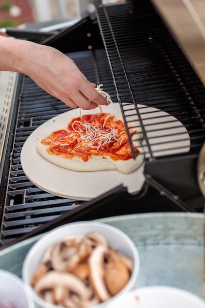 Cozinhar pizza na churrasqueira a gás ao ar livre.