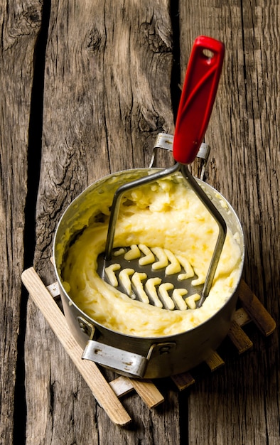 Cozinhar purê de batata com pilão em fundo de madeira