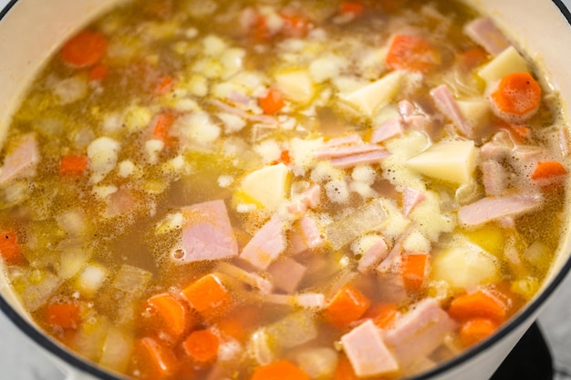 Cozinhar sopa de ervilhas em forno holandês de ferro fundido esmaltado.