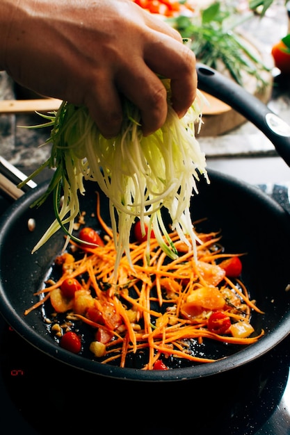 Cozinhar tomates cenoura ralada e abobrinha em uma panela mãos femininas verticais