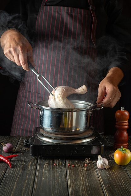 Cozinhar um delicioso caldo de pernas de frango e legumes pelas mãos de um chef na cozinha de um restaurante ou hotel