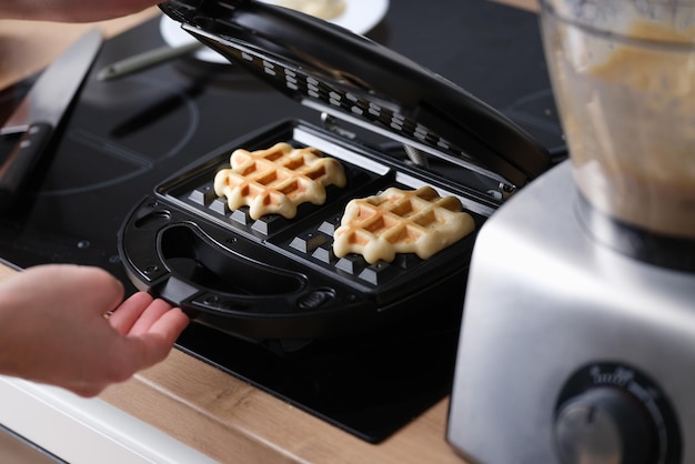 Cozinhar waffles em ferro de waffle em casa closeup