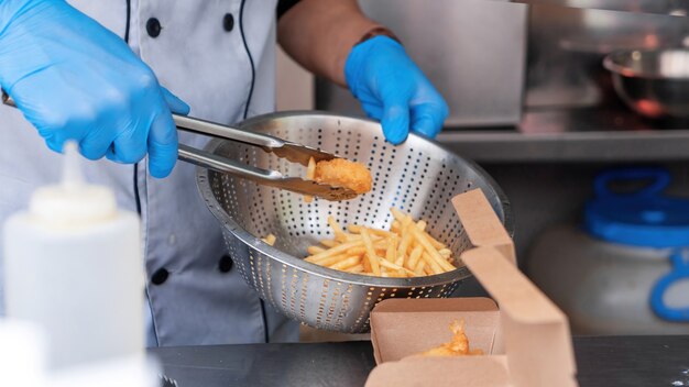 Cozinhe adicionando carne frita e batatas fritas aos pratos em um food truck