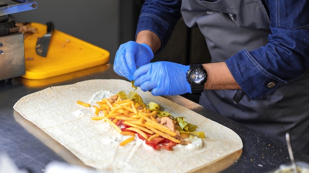 Foto cozinhe adicionando salada em um embrulho em um food truck