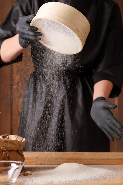 Cozinhe as mãos amassando a massa polvilhando um pedaço de massa com farinha de trigo branca Tiro baixo de perto