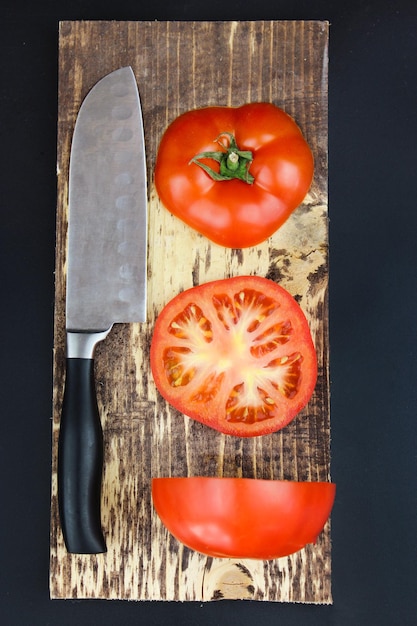 Cozinhe em uma placa de madeira fatias de tomate macro closeup Tomates frescos na tábua de corte em um fundo escuro