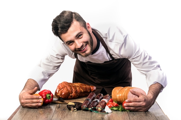 Cozinhe isolado na parede branca, sorrindo, abraçando o salame