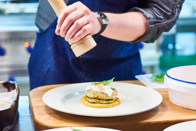 Cozinhe polvilha tempero no prato com costeleta de peixe no restaurante