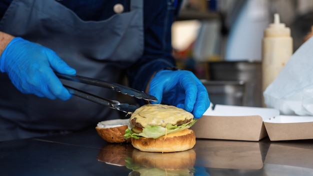 Foto cozinheira fazendo hambúrguer, adicionando hambúrguer, caminhão de comida