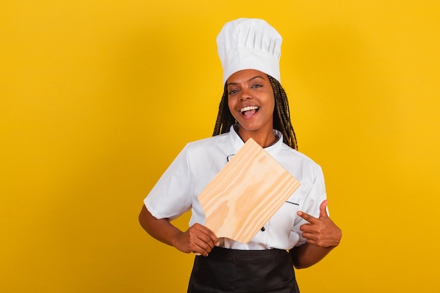 Cozinheira jovem afro-brasileira segurando tábua de madeira para gastronomia