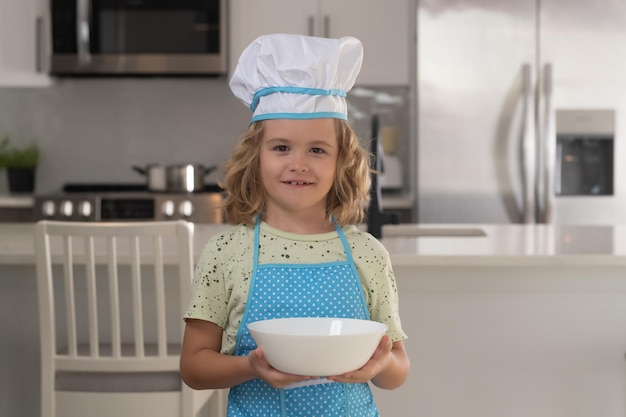 Cozinheiro chef infantil com prato de cozimento Chef infantil cozinhar culinária na cozinha Cozinhar culinária e crianças Garotinho com chapéu e avental de chefs