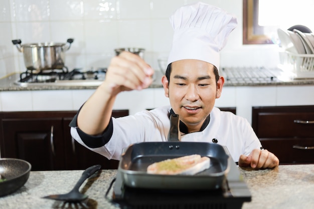 Cozinheiro chefe asiático que cozinha no restaurante da cozinha