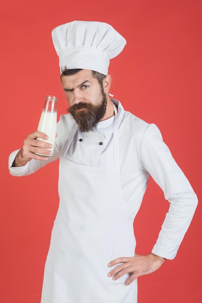 Cozinheiro chefe com rosto confiante em uniforme branco tem uma garrafa de leite fresco e proteína dieta conceito barbudo