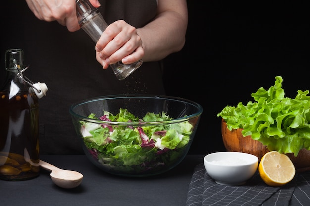 Cozinheiro chefe da mulher na cozinha que prepara a salada.