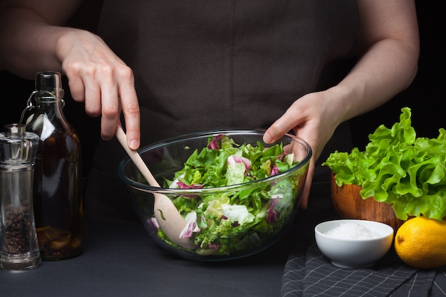 Cozinheiro chefe da mulher na cozinha que prepara a salada.